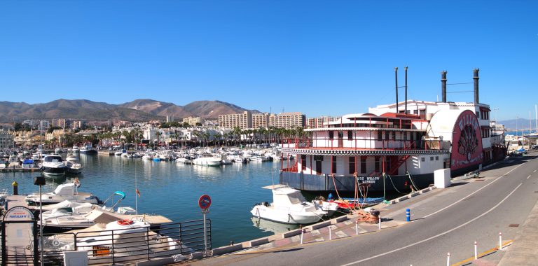 'Puerto Marina in Benalmádena, with moored boats, seafront buildings and hills behind'